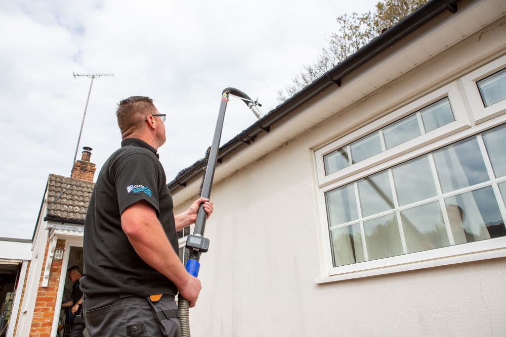 Gutter cleaning technician clearing debris from guttering